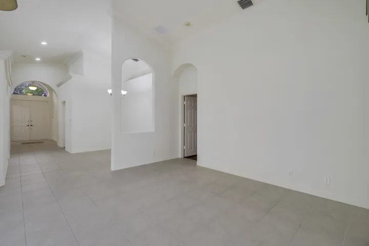Large format tile flooring, arched doorways, recessed lighting, crown molding, and double entry doors
