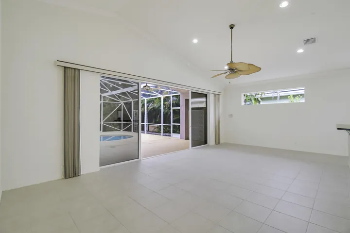 Vaulted ceiling with recessed lighting and a ceiling fan, large format tile flooring, and sliding glass doors opening to a screened enclosure with a pool and spa