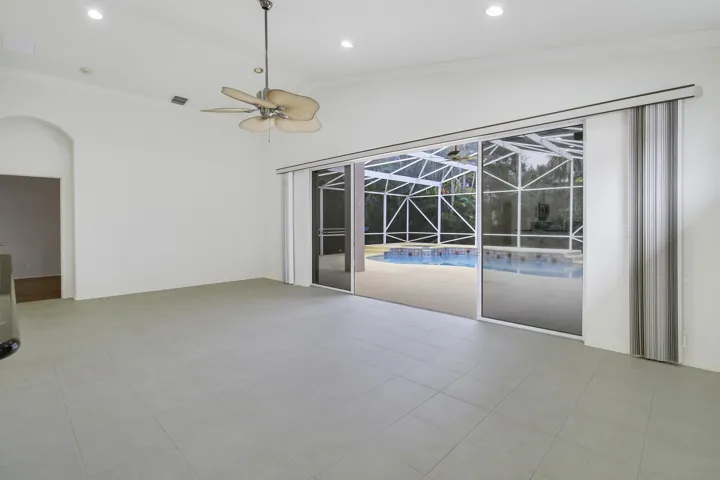 Recessed ceiling lighting, vaulted ceiling, ceiling fan, tile flooring, and sliding glass doors revealing a screened pool enclosure