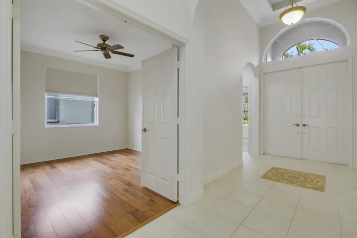 Double entry doors with an arched transom window, a tile floor entry, and high ceiling