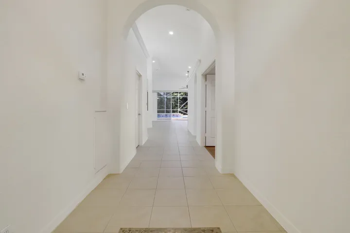 Arched entryway leading to a spacious interior with recessed lighting, tile flooring, and large glass sliding doors