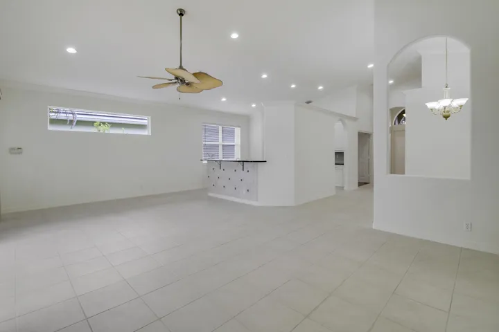 Spacious interior featuring tile flooring, vaulted ceilings, recessed lighting, and an integrated bar area with a dark countertop