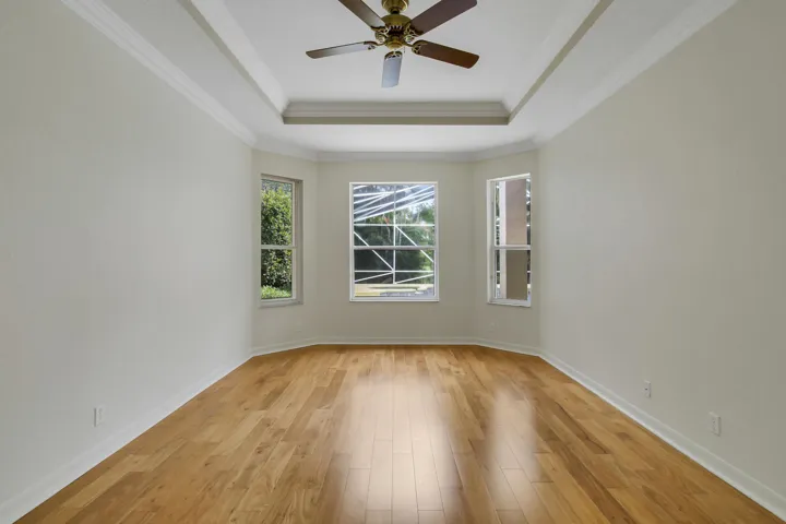 Tray ceiling with crown molding, wood-finish flooring, and bay windows in Primary Suite