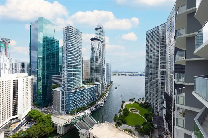 Private balconies with glass railings overlooking a waterfront cityscape and public green space