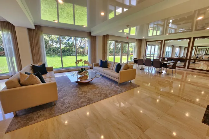 Expansive floor-to-ceiling windows, polished stone flooring, recessed lighting, and a dining area with multiple mirrors
