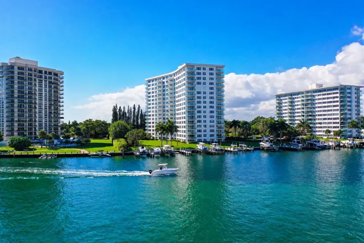 Waterfront property with multiple mid-rise buildings, manicured green spaces, and private boat docks