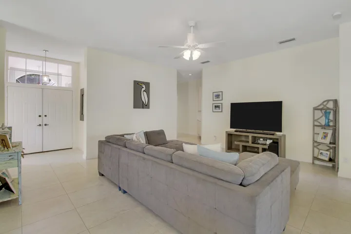 Double entry doors with transom window, tile flooring, recessed lighting, and ceiling fan