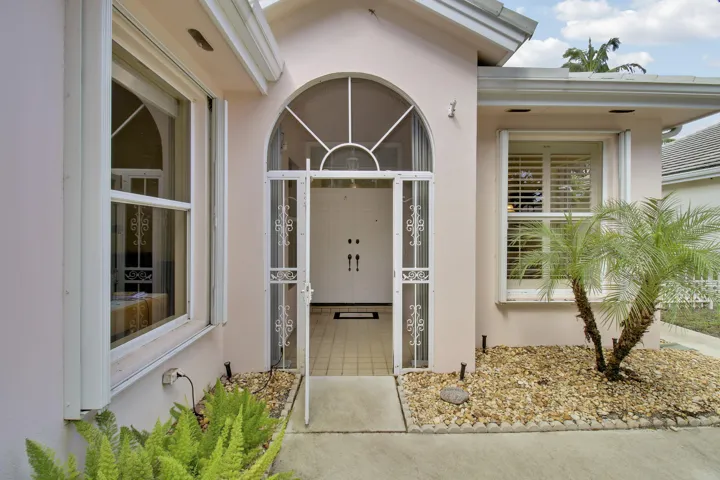Arched entry with decorative screen door leading to double entry doors