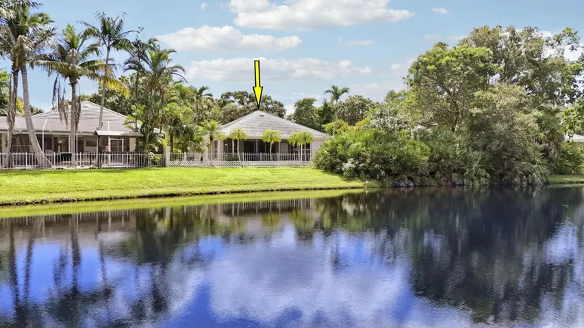 Lakeview property with screened patio, manicured lawn, and mature palm trees