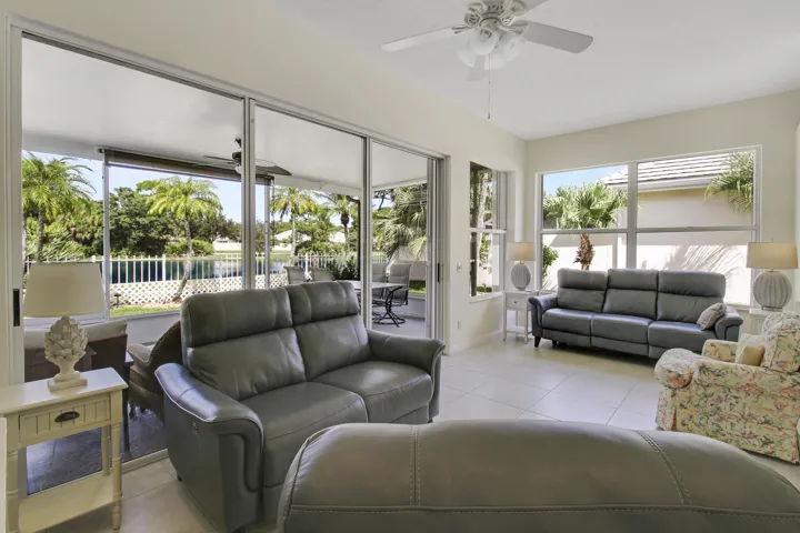Tile flooring, multiple large windows, sliding glass doors, ceiling fan, and access to an enclosed patio