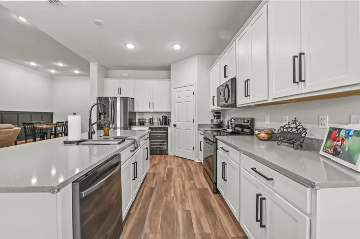 White soft close kitchen cabinets above & below counter lighting, quartz counters with oversized snack bar, built-in wine refrigerator and walk -in pantry