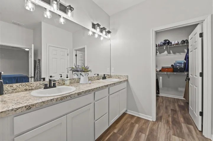 Primary bathroom has double sink vanity, separate commode area and large walk-in closet