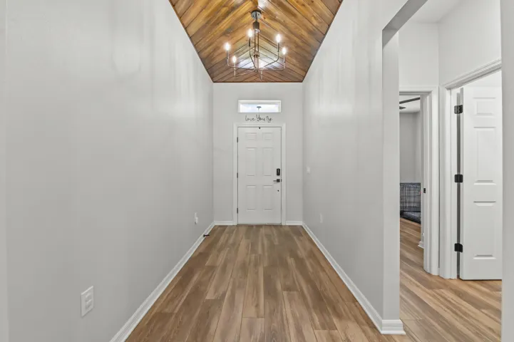 Herringbone wood ceiling in arched foyer entry leading into open living area with adjacent den converted into 5th bedroom