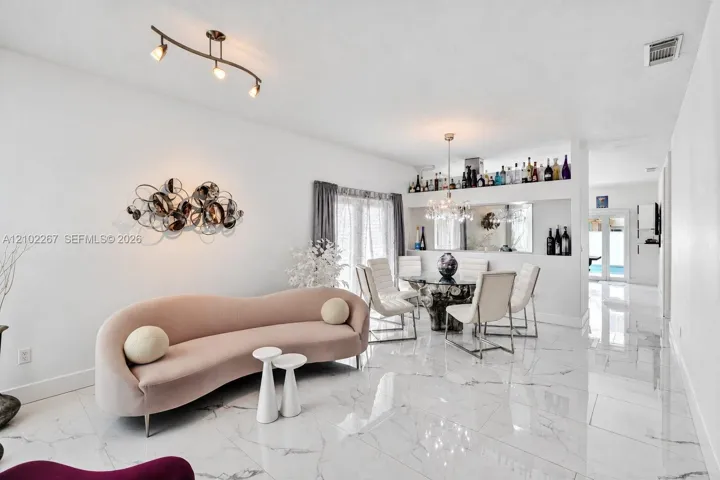 Polished stone flooring, recessed bar niche with mirrored backing, multi-point track lighting, and a tiered chandelier