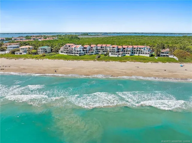 Elevated aerial view outlines the residence and showcases its close proximity to the community pool and beach.