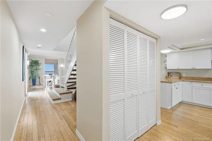 Wood flooring carries through the main level, with the open staircase and ocean visible ahead.