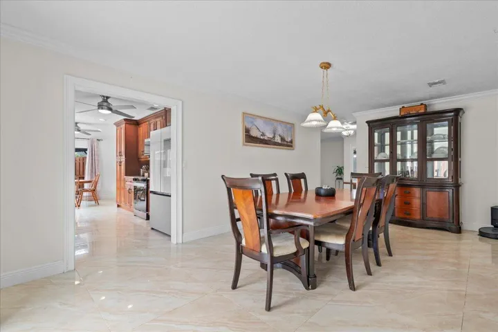 Open concept dining area featuring crown molding, neutral wall tones, and polished tile flooring
