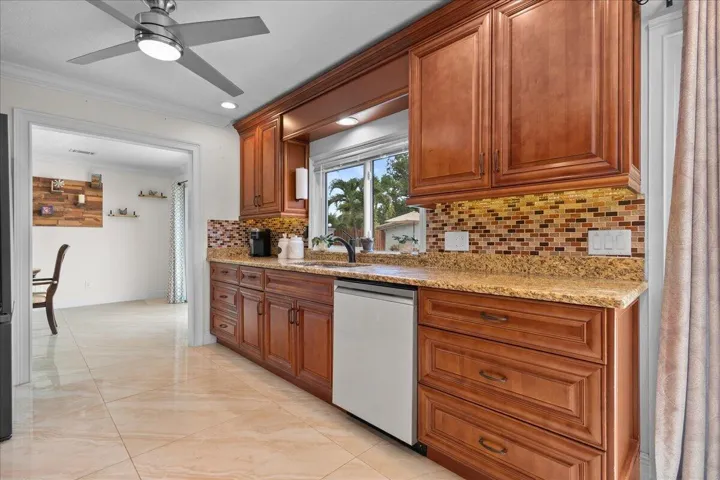 Wood-finish cabinetry with a built-in window valance, granite-finish countertops, and a mosaic tile backsplash