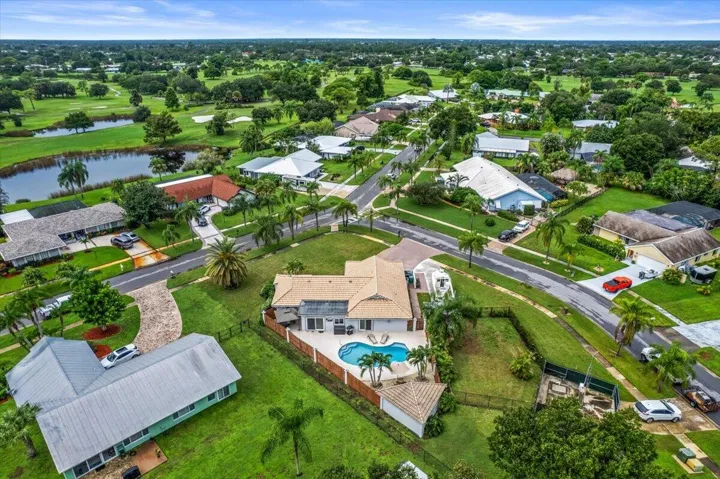 Lush green landscaping with mature trees, paved streets, and a residential neighborhood setting