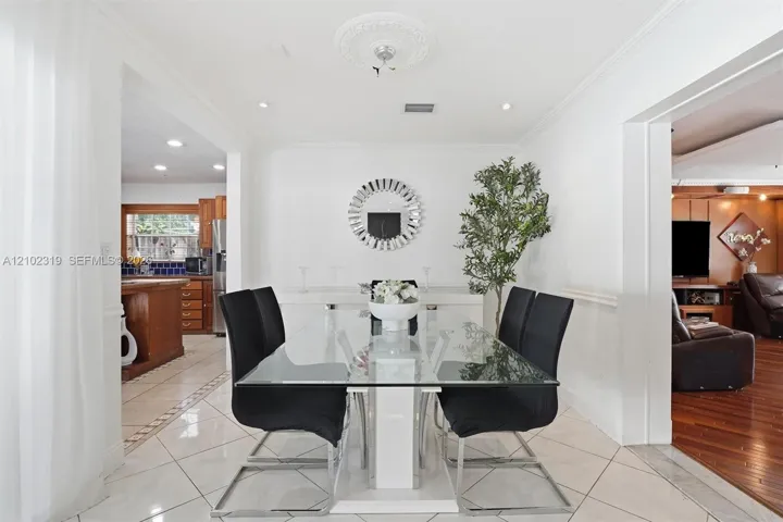 Dining area featuring polished large-format tile flooring, a decorative ceiling medallion, crown molding, and recessed lighting
