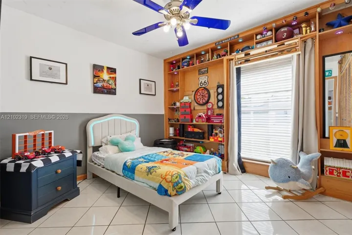 Floor-to-ceiling wooden built-in shelving, tile flooring, and a multi-blade ceiling fan with integrated lighting