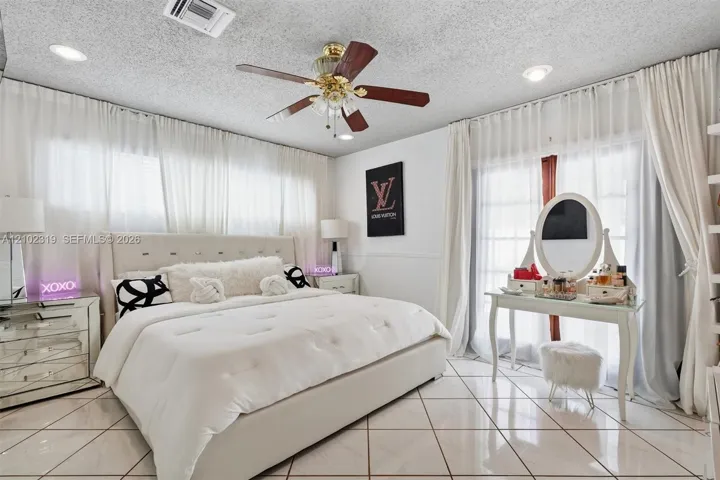 Neutral-tone tile flooring, ceiling fan with light fixture, recessed lighting, and sliding glass doors