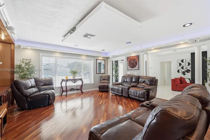 Wood-finish flooring, recessed lighting, crown molding with integrated ambient lighting, and neutral wall tones