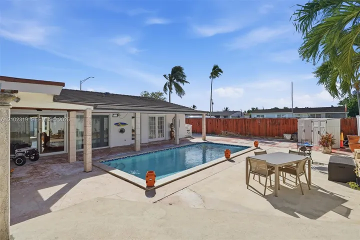 Outdoor swimming pool featuring a concrete deck and a covered patio area with supporting columns