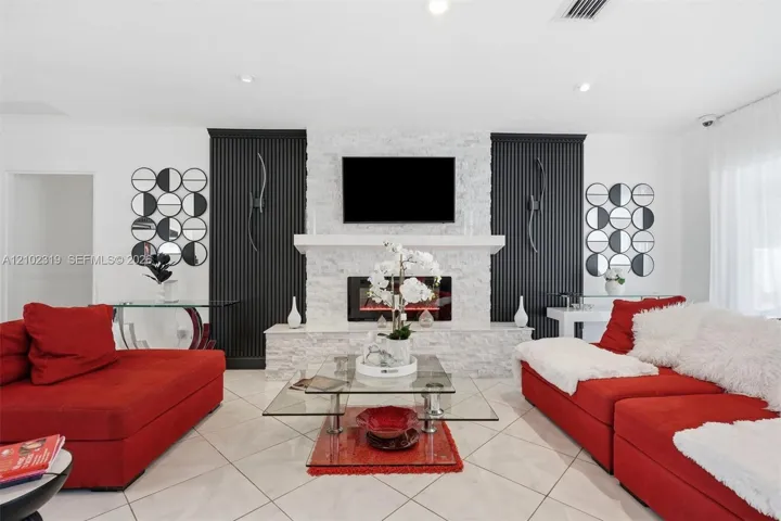 Floor-to-ceiling fireplace featuring textured stone masonry, recessed electric firebox, and a prominent mantel, flanked by vertical slat architectural detailing and polished tile flooring