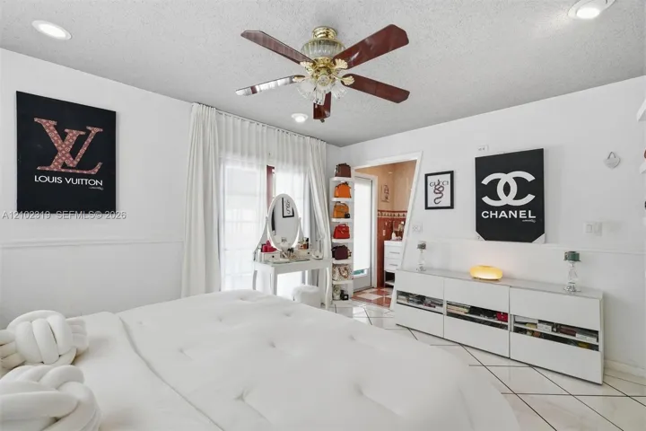 Neutral white interior featuring tile flooring, recessed ceiling lighting, a multi-blade ceiling fan with integrated lighting, and white wainscoting