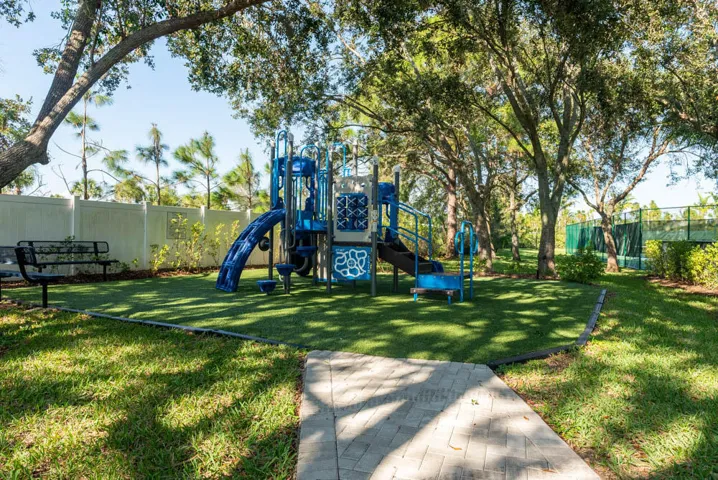 Recreational playground featuring a multi-level structure with slides and climbing elements, surrounded by synthetic turf surfacing