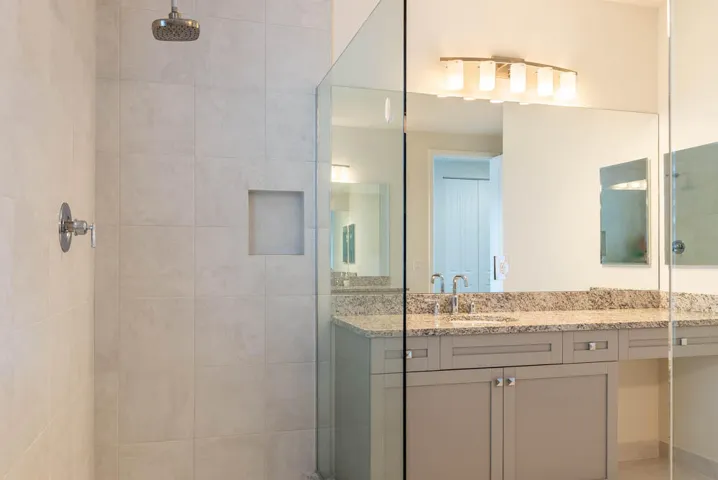 Glass-enclosed shower with a rainfall showerhead and tiled niche