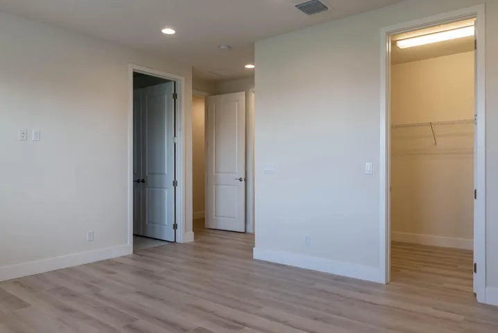 Neutral-toned walls, wood-finish flooring, recessed lighting, and a closet with built-in shelving