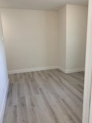 Light-toned wood-finish flooring with white trim and neutral wall paint