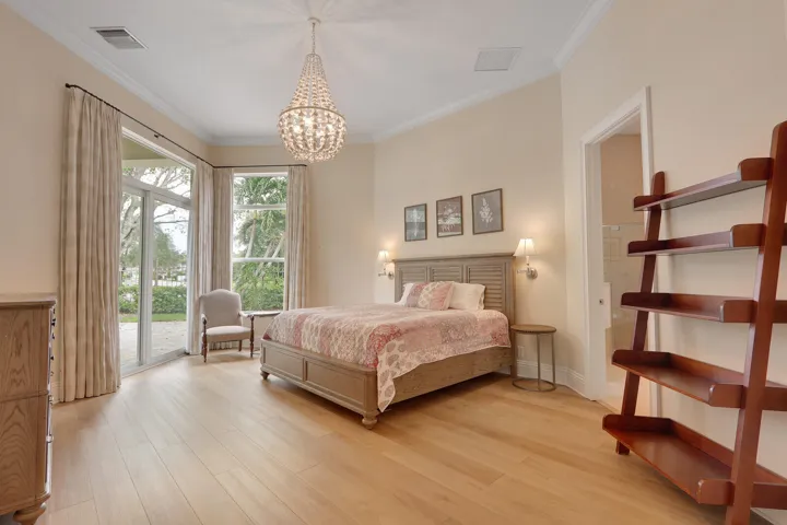 Light-toned wood-finish flooring, large sliding glass doors, a window with a garden outlook, a decorative chandelier, and wall-mounted sconces