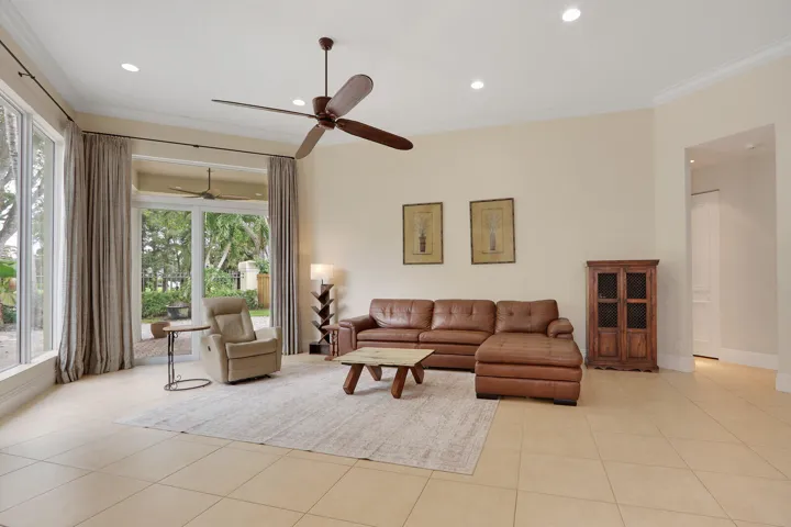 Spacious living area featuring tile flooring, expansive impact windows throughout, recessed lighting, and ceiling fans