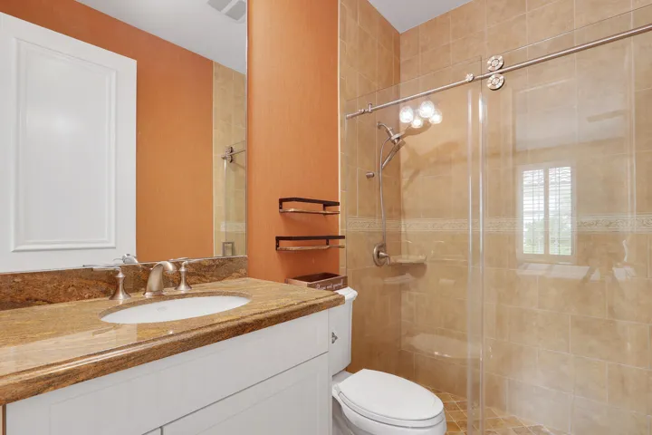 Vanity with an undermount sink and stone countertop, tile-surround shower with a glass enclosure, and a wall-mounted medicine cabinet