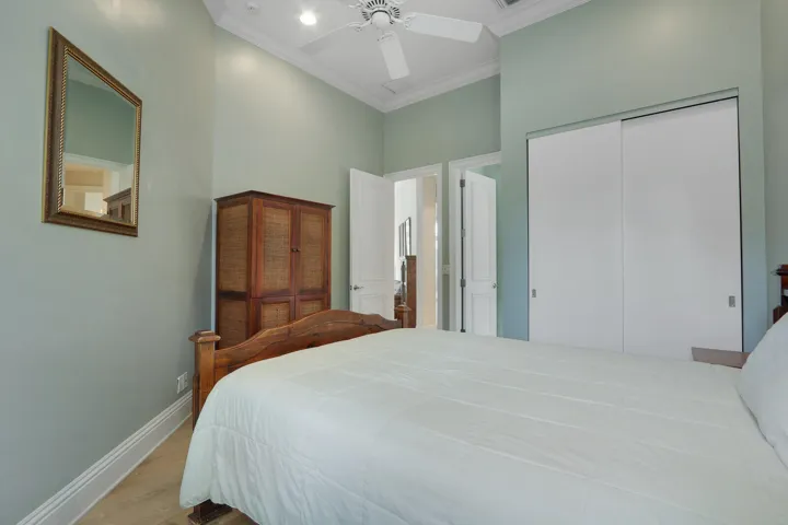Vaulted ceilings with crown molding, ceiling fan, wood-finish flooring, and white sliding closet doors