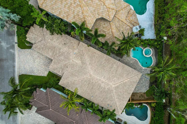 Tile rooflines, paver driveway, lush landscaping, freeform pool, and integrated spa