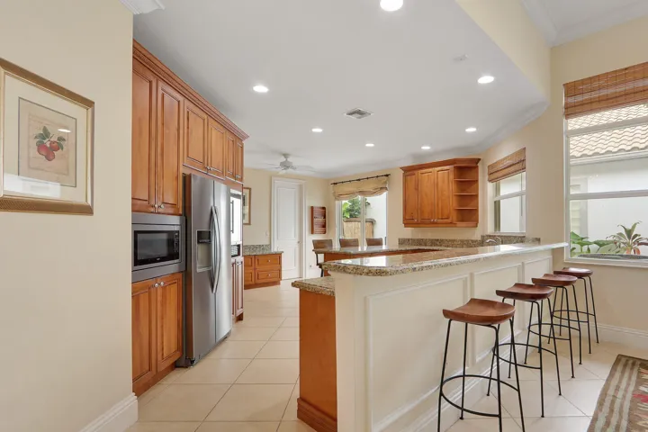 Kitchen featuring wood cabinetry, stainless steel appliances, a breakfast bar with stone countertops, and recessed lighting