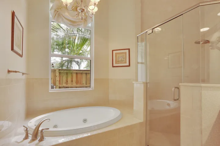 Built-in soaking tub with deck-mounted faucet, glass-enclosed shower, and tiled surround