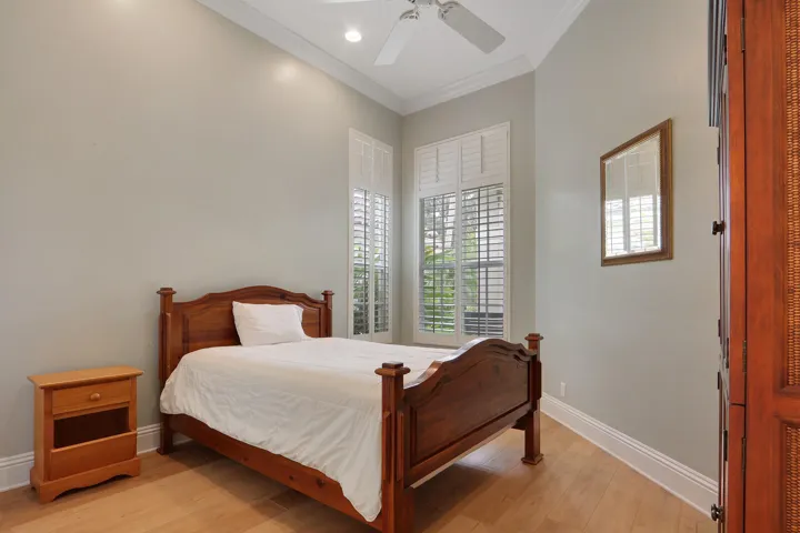 Vaulted ceiling with crown molding, wood-finish flooring, plantation shutters, recessed lighting, and a ceiling fan