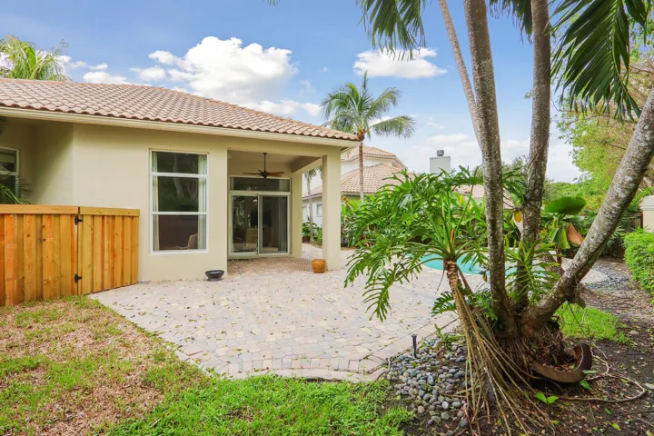 Tiled roof structure, covered patio with ceiling fan, sliding glass doors, large windows, and a paved patio area
