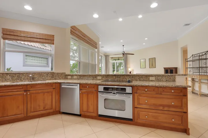 Kitchen featuring wood cabinetry, granite countertops, tile flooring, stainless steel appliances, and recessed lighting