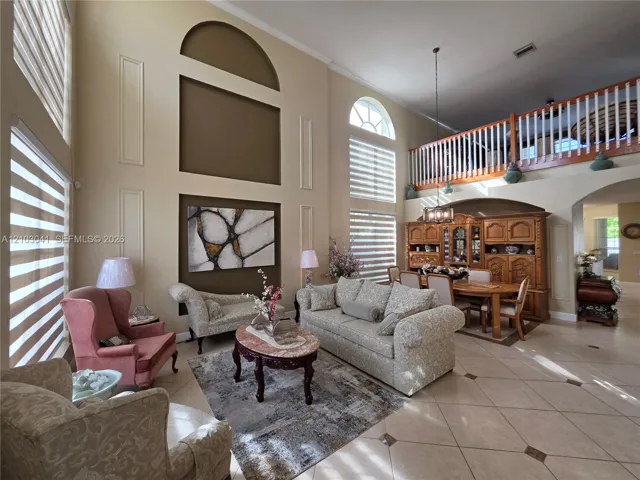 Soaring ceilings, arched windows, and a decorative wall paneling accent a bright living space