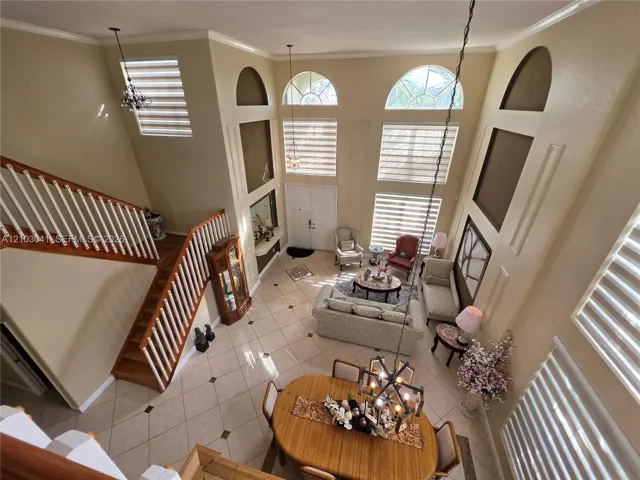 Two-story entry with a wood staircase, arched windows, and tile flooring