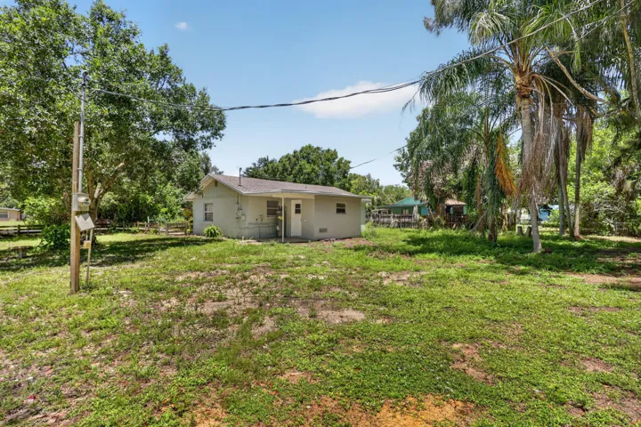 Expansive grassy lot with mature trees and a single-story residence