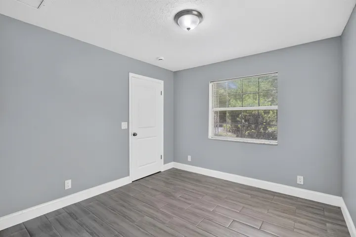 Interior room featuring wood-finish flooring, light gray wall paint, and white trim