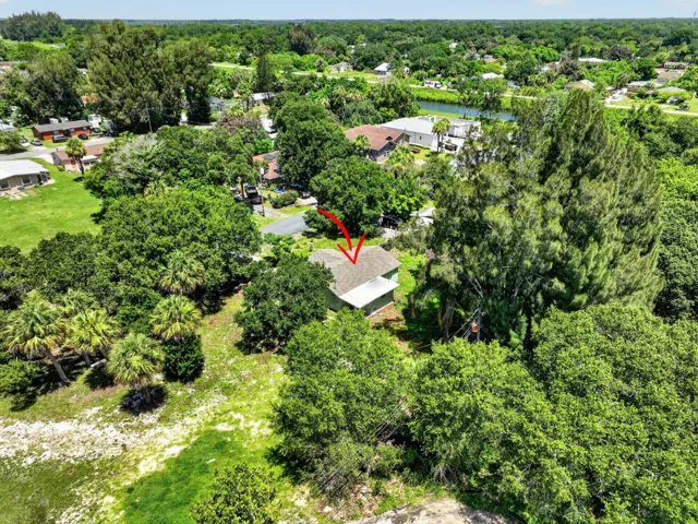 Aerial view showcasing a residential property surrounded by mature trees and lush greenery