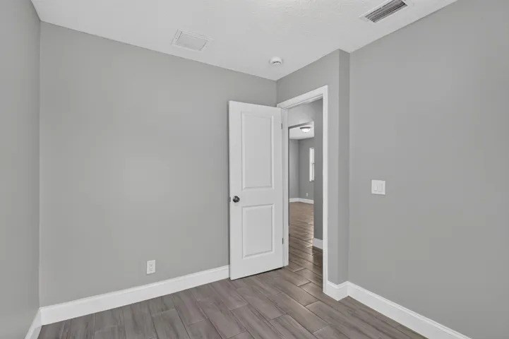 Interior room featuring wood-finish tile flooring, light gray wall paint, and white trim